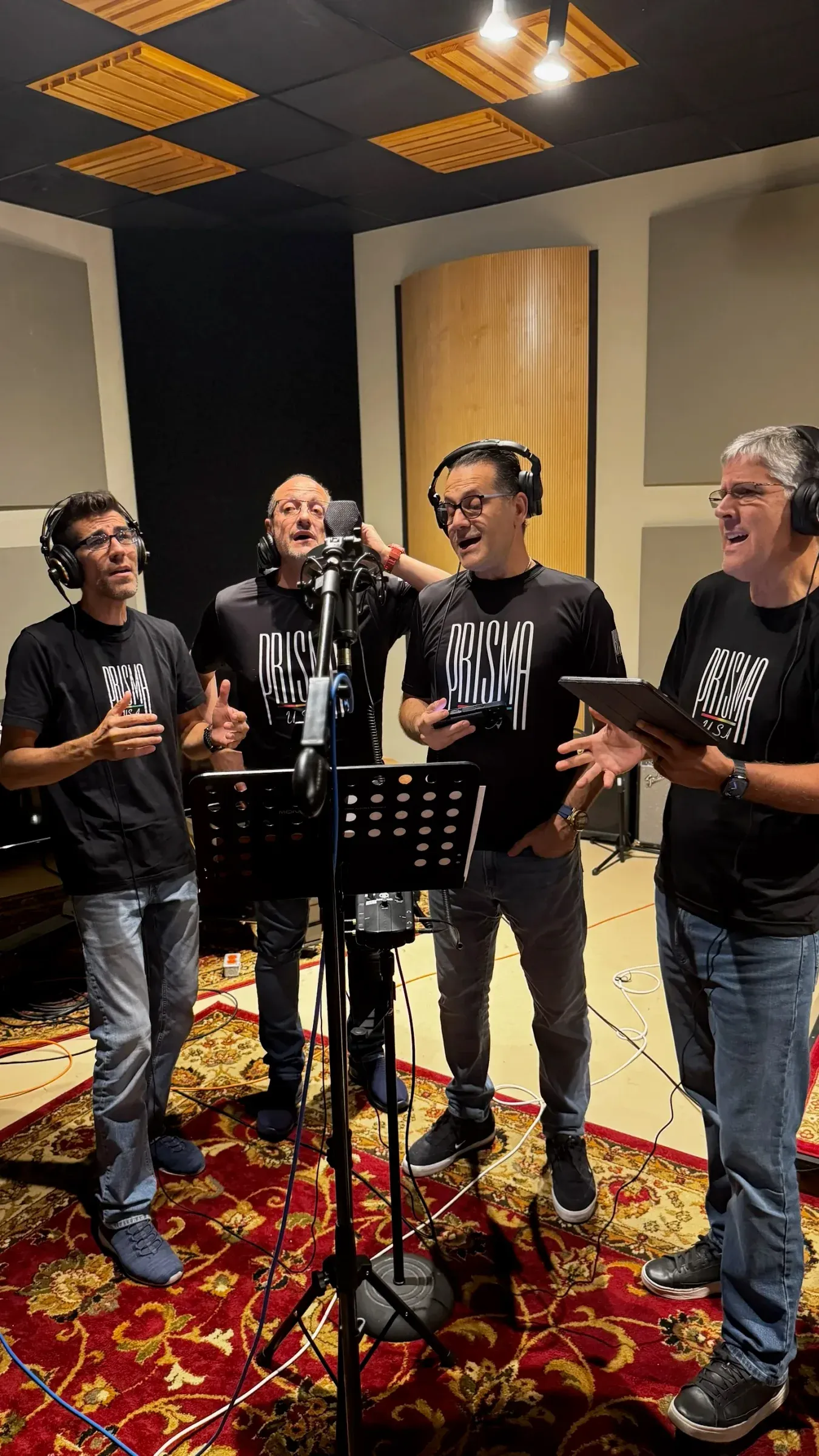 Four singers around one microphone in the studio