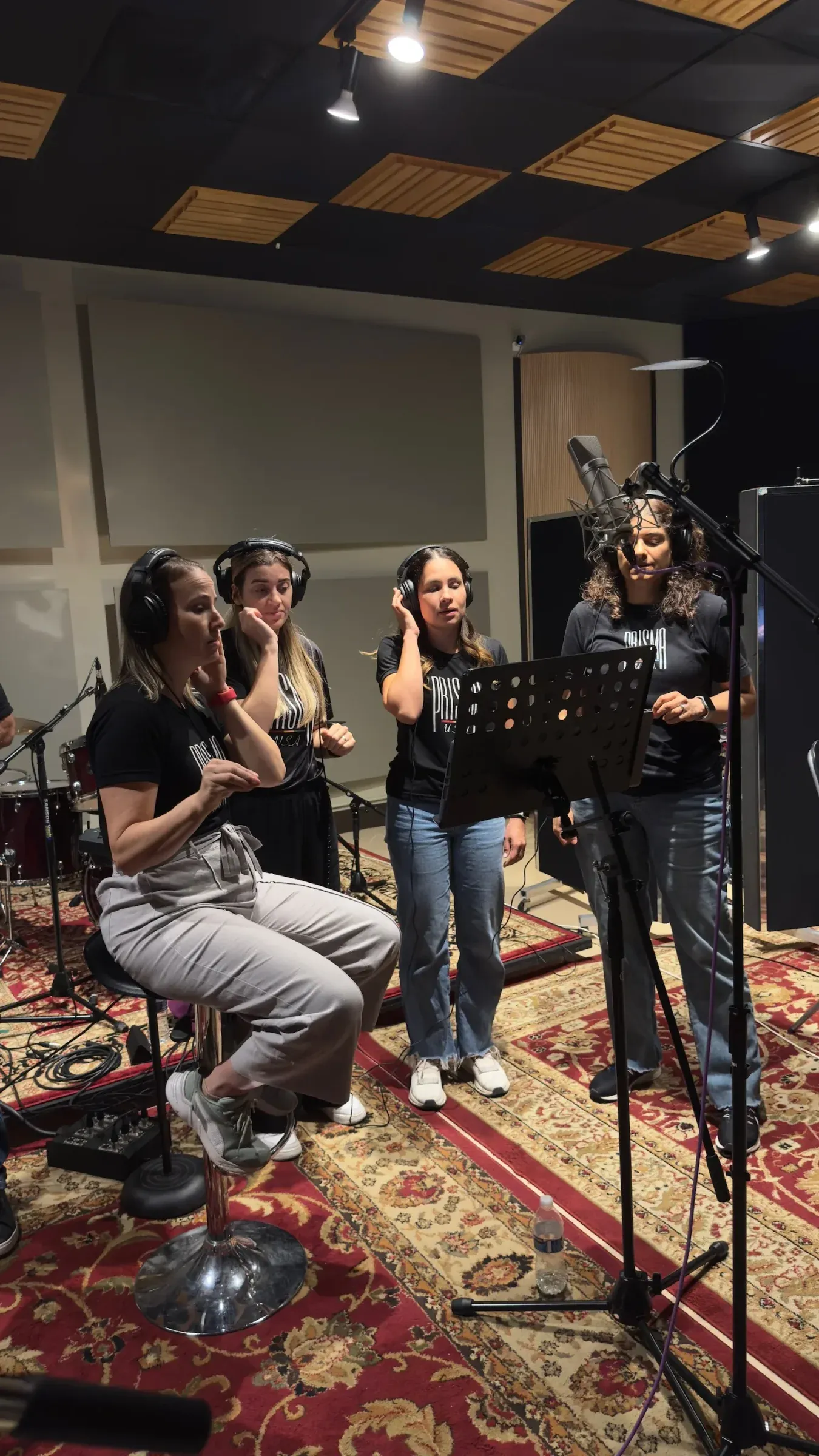 Singers gathered around a music stand in the studio