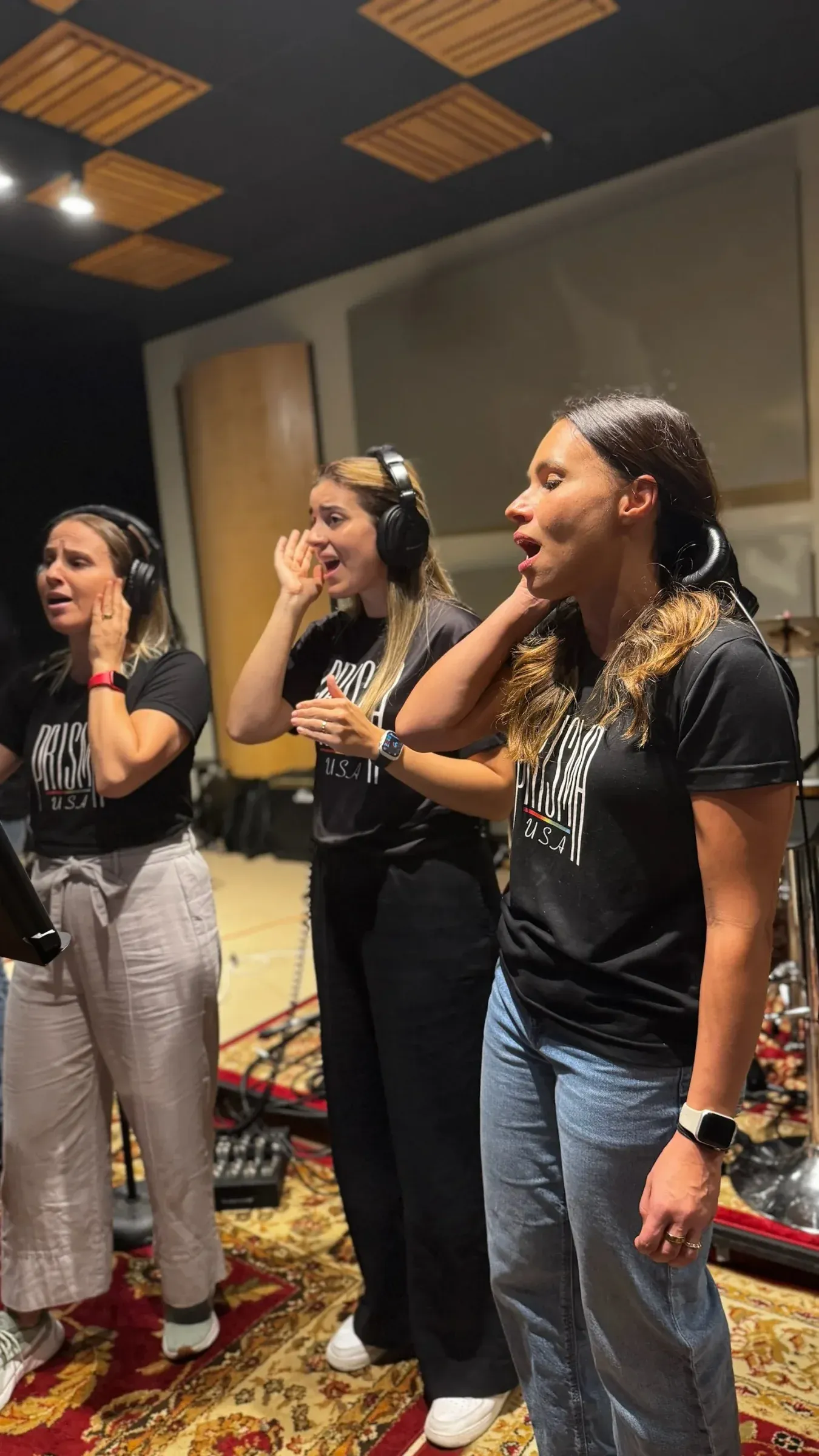 Three singers in headphones at the studio microphone